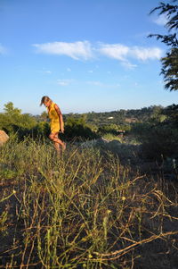 Woman walking on grassy field against sky