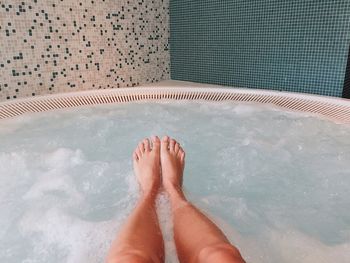 Low section of woman relaxing in bathtub