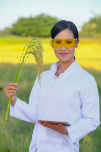 Portrait of smiling young woman holding umbrella on field