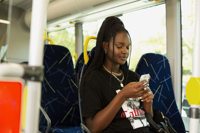 Young woman using cell phone in bus