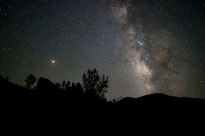 Low angle view of silhouette mountain against star field