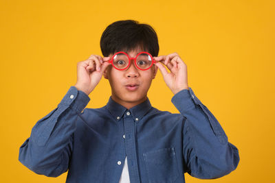 Portrait of boy holding yellow against orange background