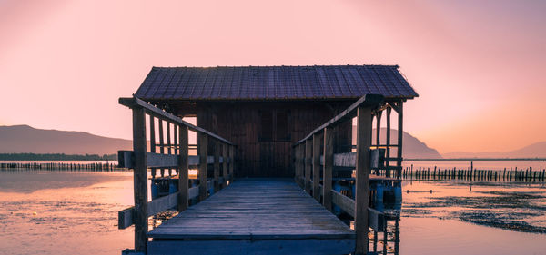 Old hut at beach against sky during sunset