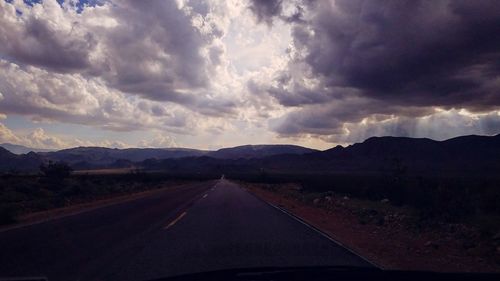 Road by mountains against sky