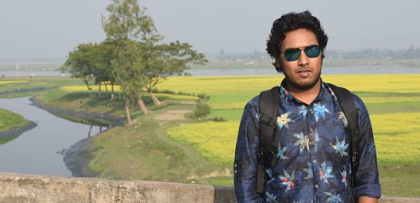 Portrait of man in sunglasses standing against landscape