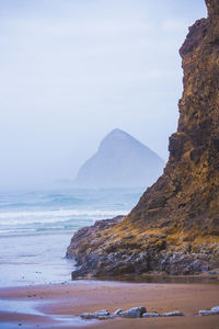 Rock formation at beach against sky