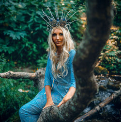 Portrait of young woman sitting on tree