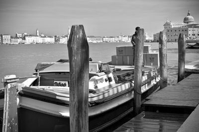 Boats moored at harbor in city against sky