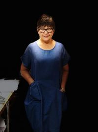 Portrait of smiling senior woman standing in darkroom