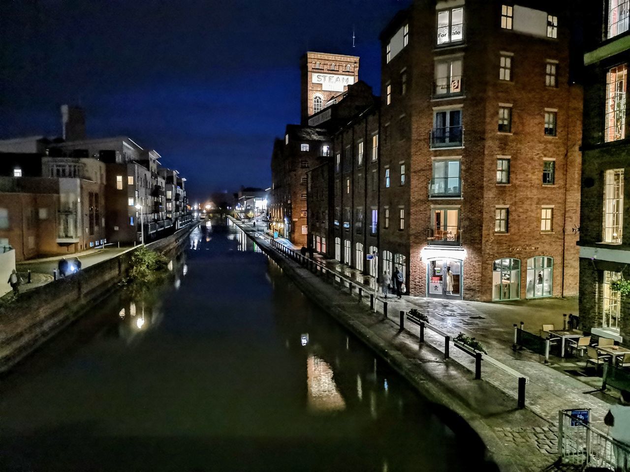 CANAL AMIDST BUILDINGS AGAINST SKY AT NIGHT
