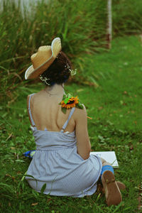 Rear view of woman sitting on field