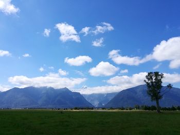 Scenic view of field and mountains against blue sky