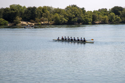 People in boat on river against trees