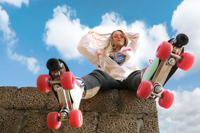 Young woman wearing roller skate against sky