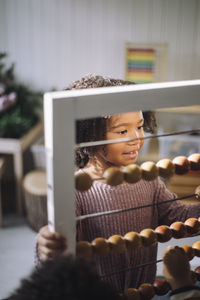 Schoolgirl using abacus in classroom at kindergarten