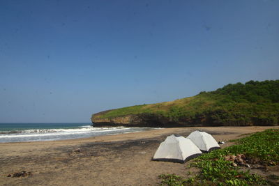 Scenic view of beach against clear blue sky