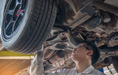 Low angle view of man repairing car in garage