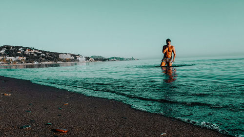 Men standing on beach against clear sky