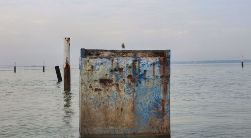 Wooden posts on sea against sky