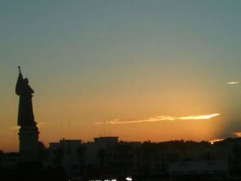 Silhouette of statue against sky at sunset