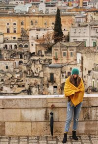 Full length of woman standing on terrace against buildings in city