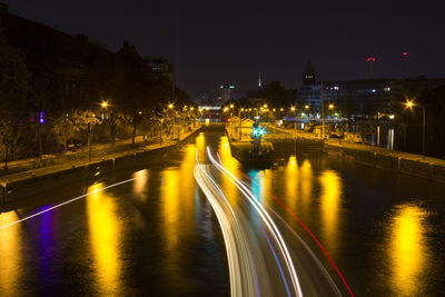 Light trails on bridge over river in city at night