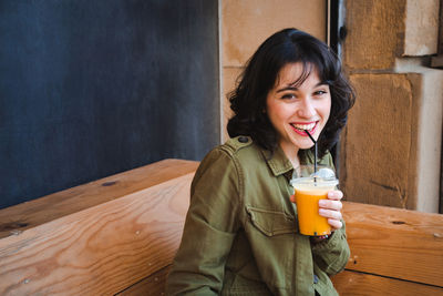 Portrait of smiling young woman drinking drink