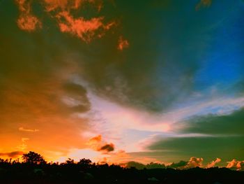 Low angle view of silhouette trees against dramatic sky