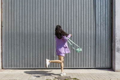 Mid adult woman dancing in front of gray wall