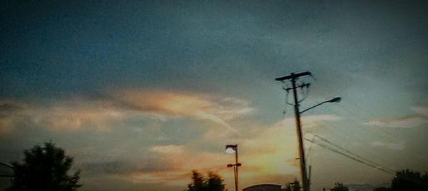 Low angle view of power lines against cloudy sky