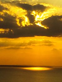 Scenic view of sea against dramatic sky during sunset