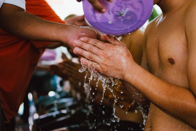 Midsection of shirtless man washing hands with water