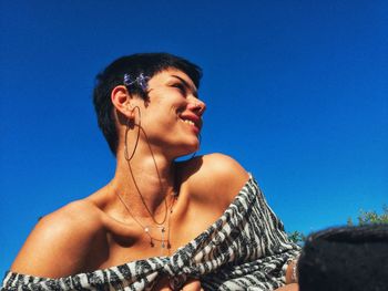 Low angle view of smiling man looking away against blue sky