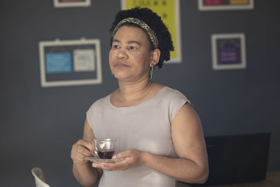 Portrait of woman holding drink at home