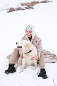 Young beautiful woman and her golden retriever dog having fun in winter.