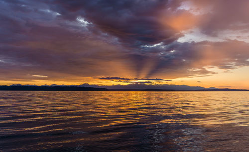 Scenic view of sea against dramatic sky during sunset