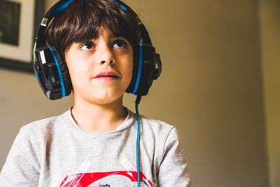 Boy looking away while wearing headphones at home