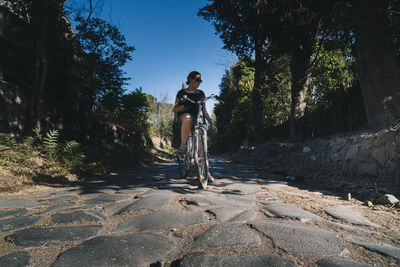 Man riding bicycle on road amidst trees