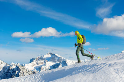 Full length of man standing on snowcapped mountain against sky