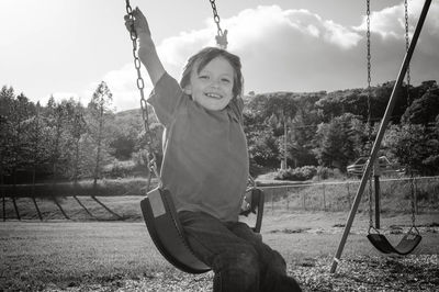 Portrait of cute boy sitting on swing at playground