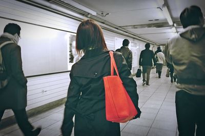 Rear view of people walking on railway station platform