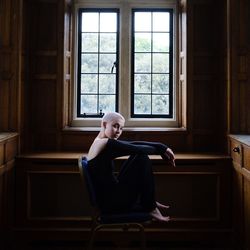 Side view of man sitting on chair at home