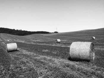 Hay bales on field against clear sky