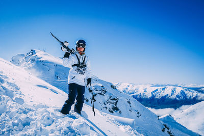 Man standing on snowcapped mountain against blue sky