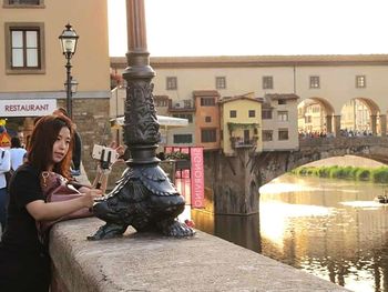 Woman sitting by statue in city