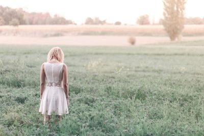 Rear view of young woman standing on field