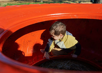 Cute boy playing inside and over a colorful tractor wheel at the farm fair on halloween