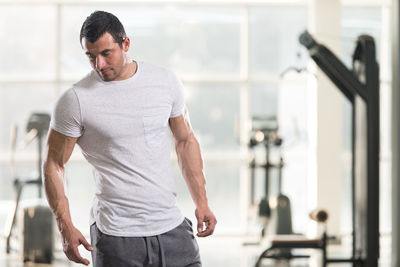 Muscular man looking away while standing in gym