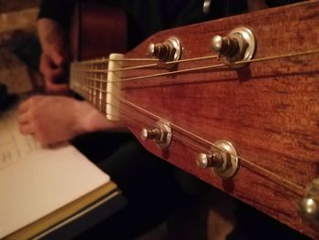 Close-up of man playing guitar at home