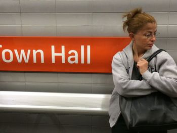 Woman standing against text on wall at subway station